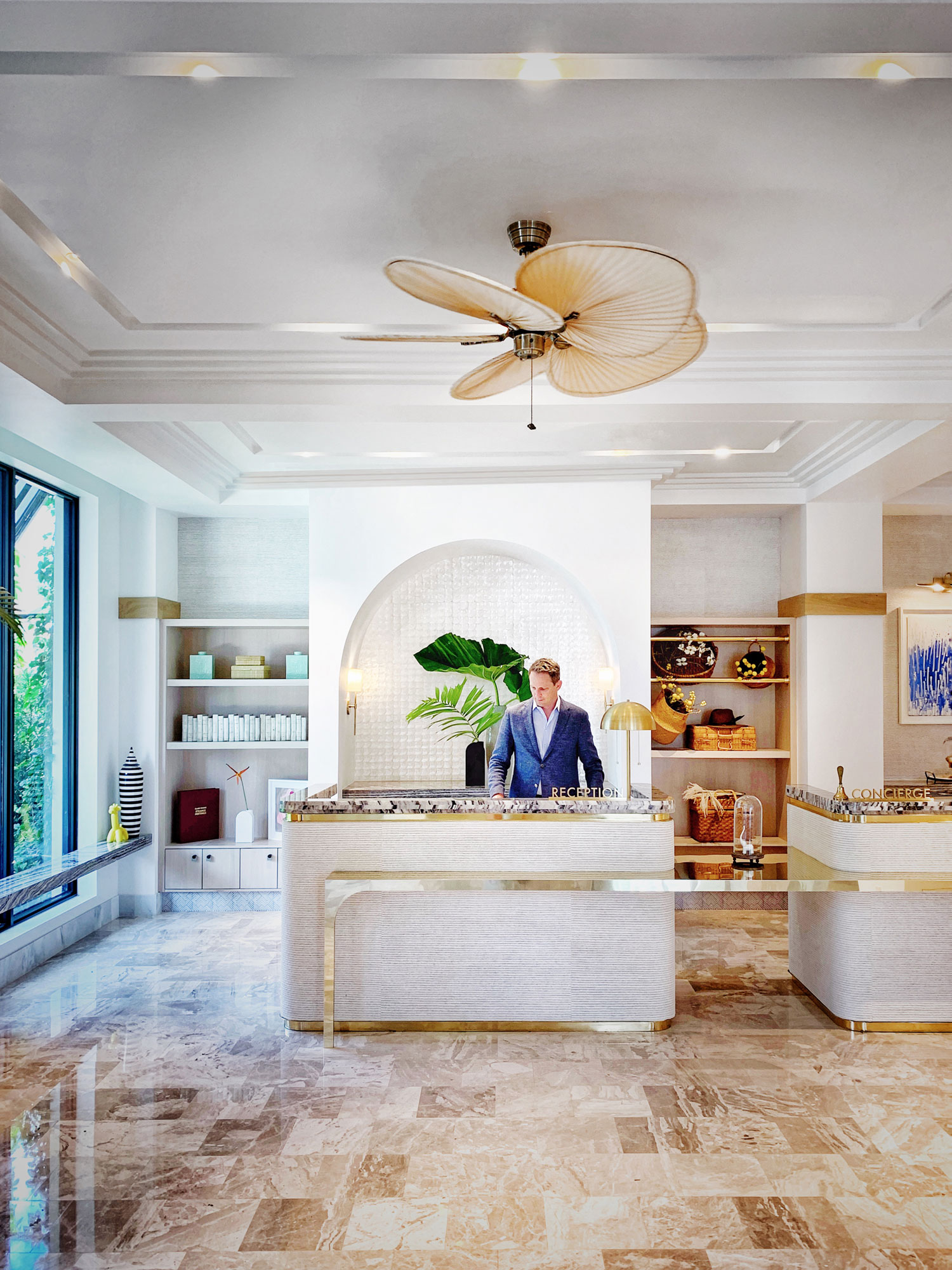 Concierge desk at the White Elephant Palm Beach with a gentlement standing behind cream colored desk