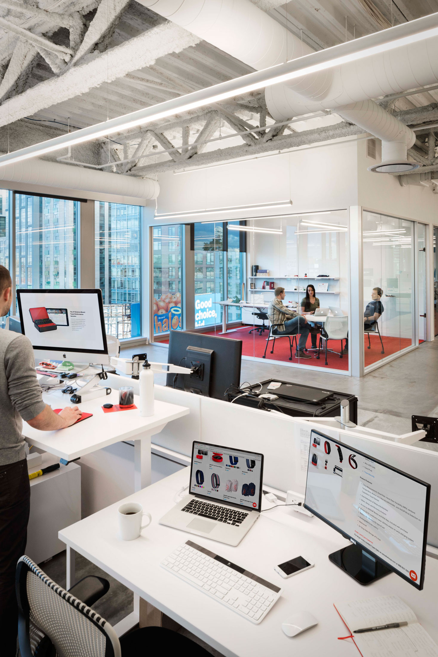 A workstation looking into a glass-walled meeting room